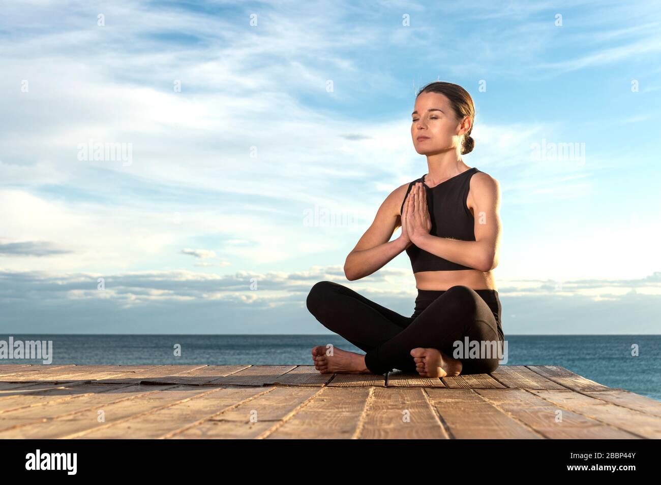 donna che pratica la meditazione mattutina in natura dal mare, sano concetto di stile di vita. Foto Stock
