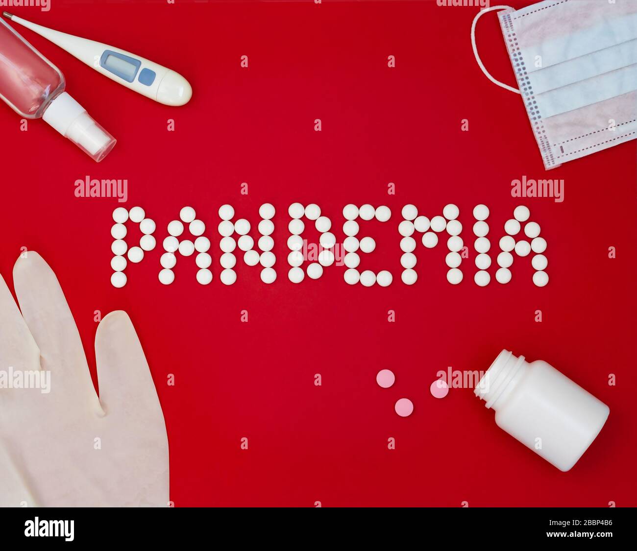 Frase di testo Pandemia su sfondo rosso con medicinali, antisettico per le mani, termometro e maschera protettiva. Foto Stock