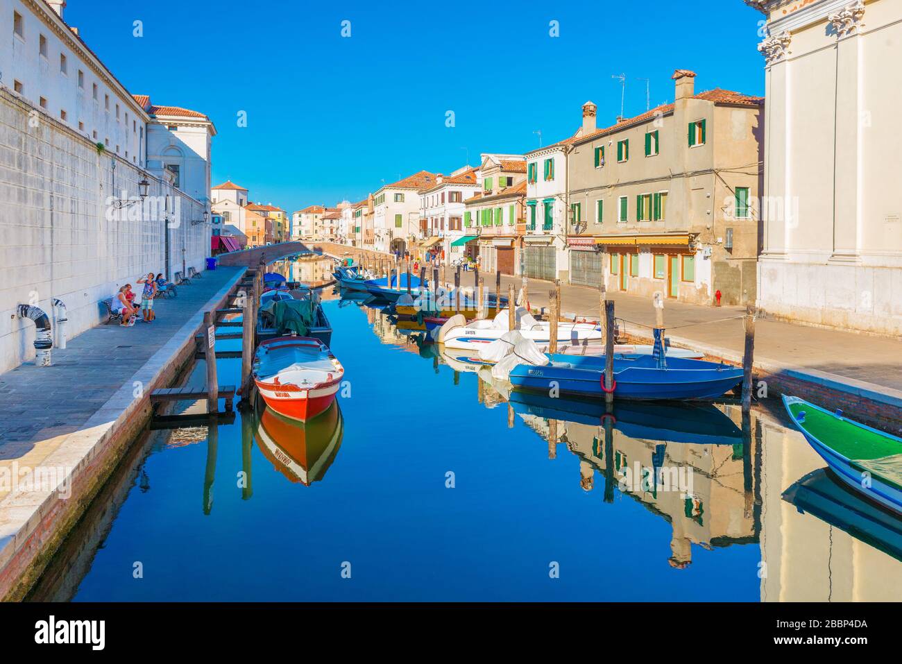 Chioggia - Settembre 2016, Italia: Canal con barche in acqua nel centro storico di Chioggia. La gente cammina lungo il lungomare Foto Stock