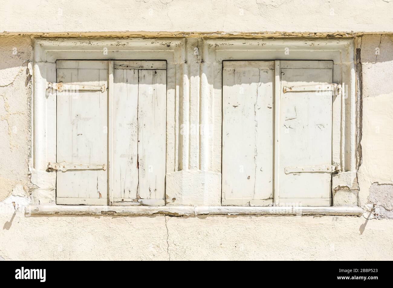 Facciata di casa abbandonata e fatiscente con 2 finestre con persiane Foto Stock