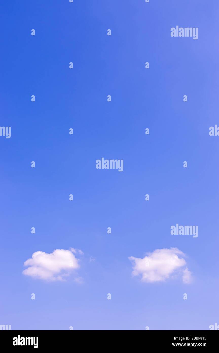Cielo blu al sole con due piccole nuvole bianche, come nuvole di pensiero o bolle vocali, con molto spazio di copia Foto Stock