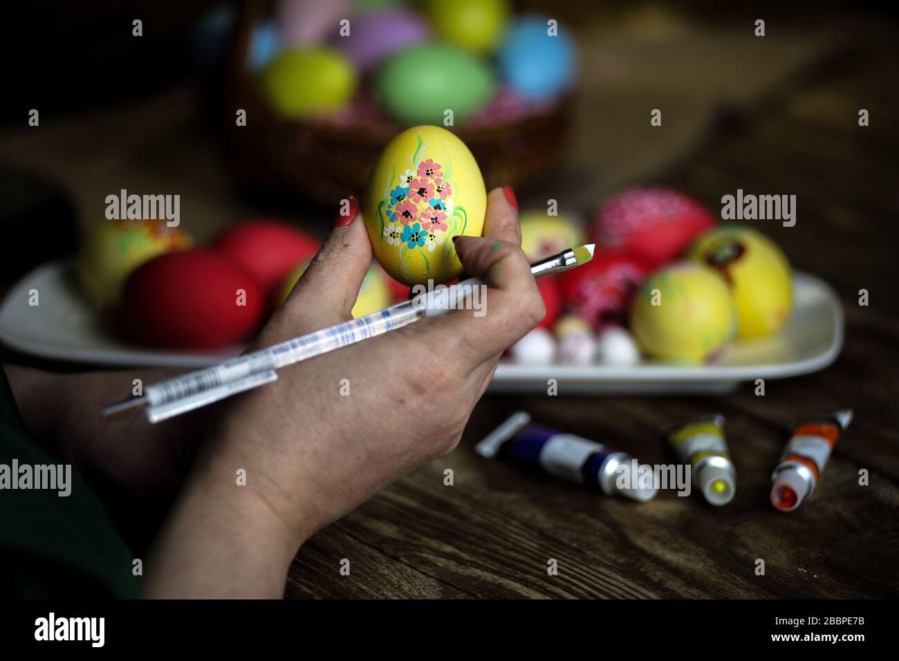 Le mani della donna tengono le uova con i motivi floreali. Preparazione per la Pasqua. Artista dipinge un uovo di Pasqua. Primo piano. Messa a fuoco selettiva. Spazio di copia. Orizzontale Foto Stock