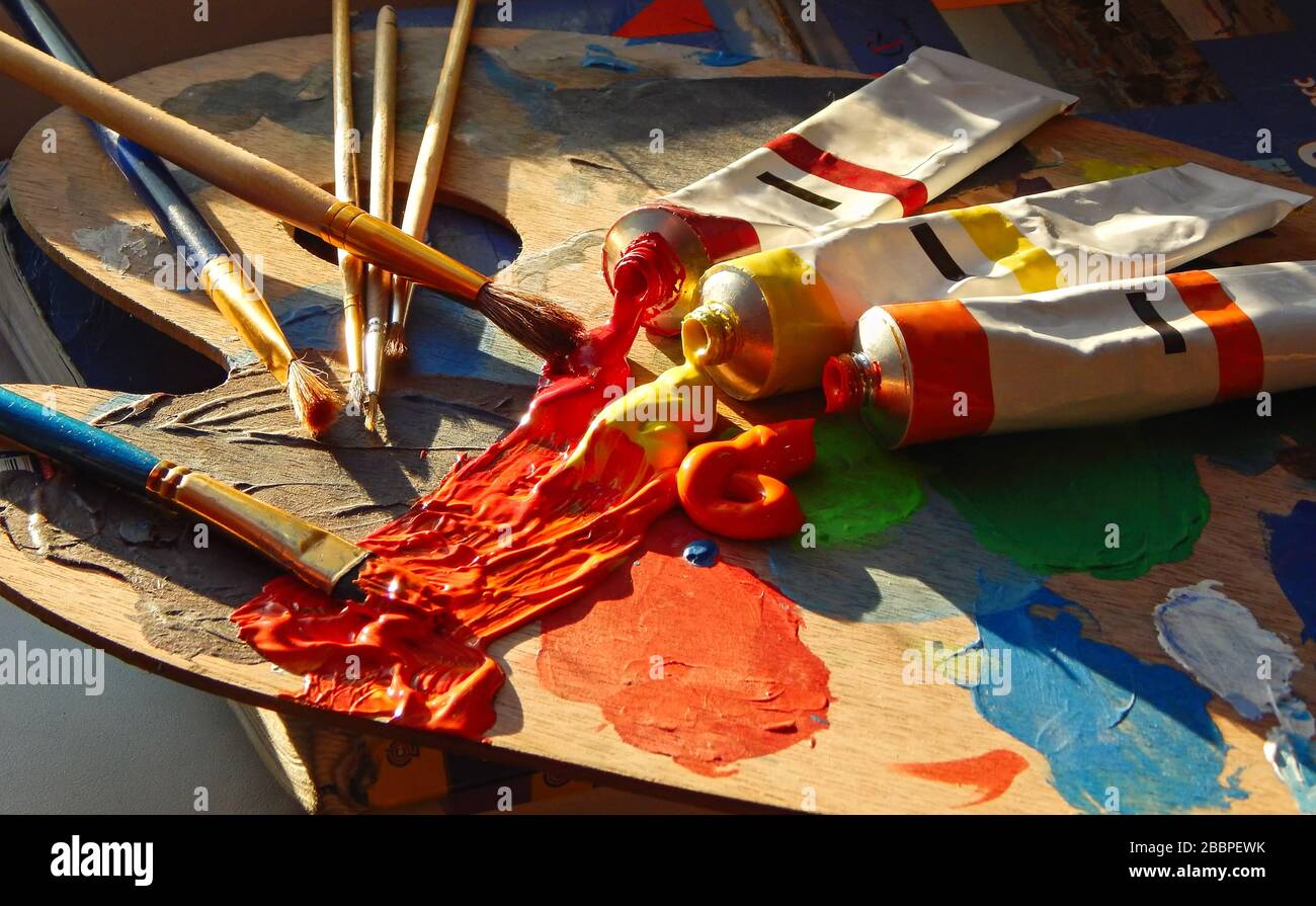 Pennelli, palette d'artista, dipinti ad olio su scrivania in studio pittore. Primo piano. Foto Stock