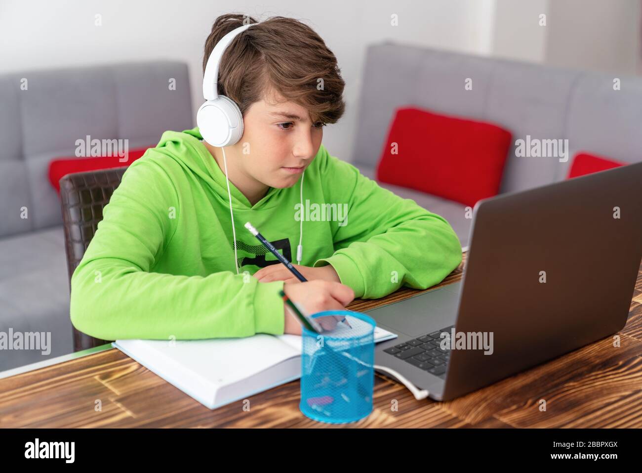 Giovane ragazzo sta studiando di fronte al laptop. E learning, studio a casa online Foto Stock