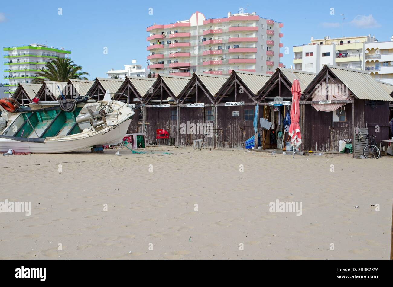 Monte Gordo, Portogallo - 18 novembre 2019: Una barca da pesca in riparazione accanto alle capanne dei pescatori sulla spiaggia sabbiosa di Monte Gordo sulla A del Portogallo Foto Stock