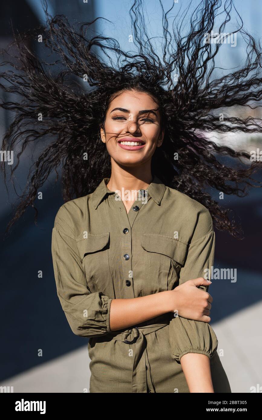 Giovane donna attraente con i suoi capelli ondulati nel vento sorridente Foto Stock