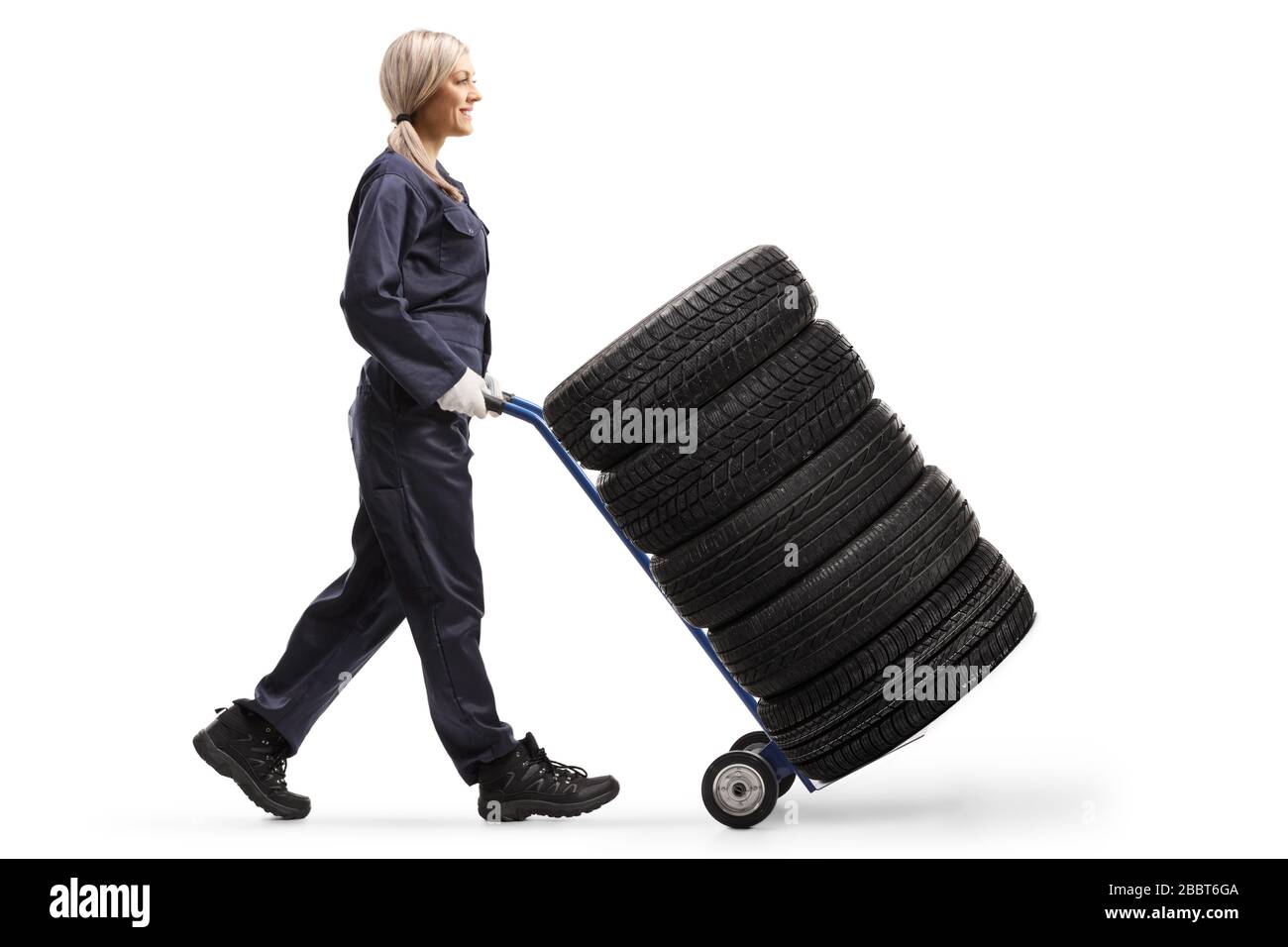 Profilo a lunghezza intera di una macchina meccanica femminile che cammina e spinge pneumatici su un camion a mano isolato su sfondo bianco Foto Stock