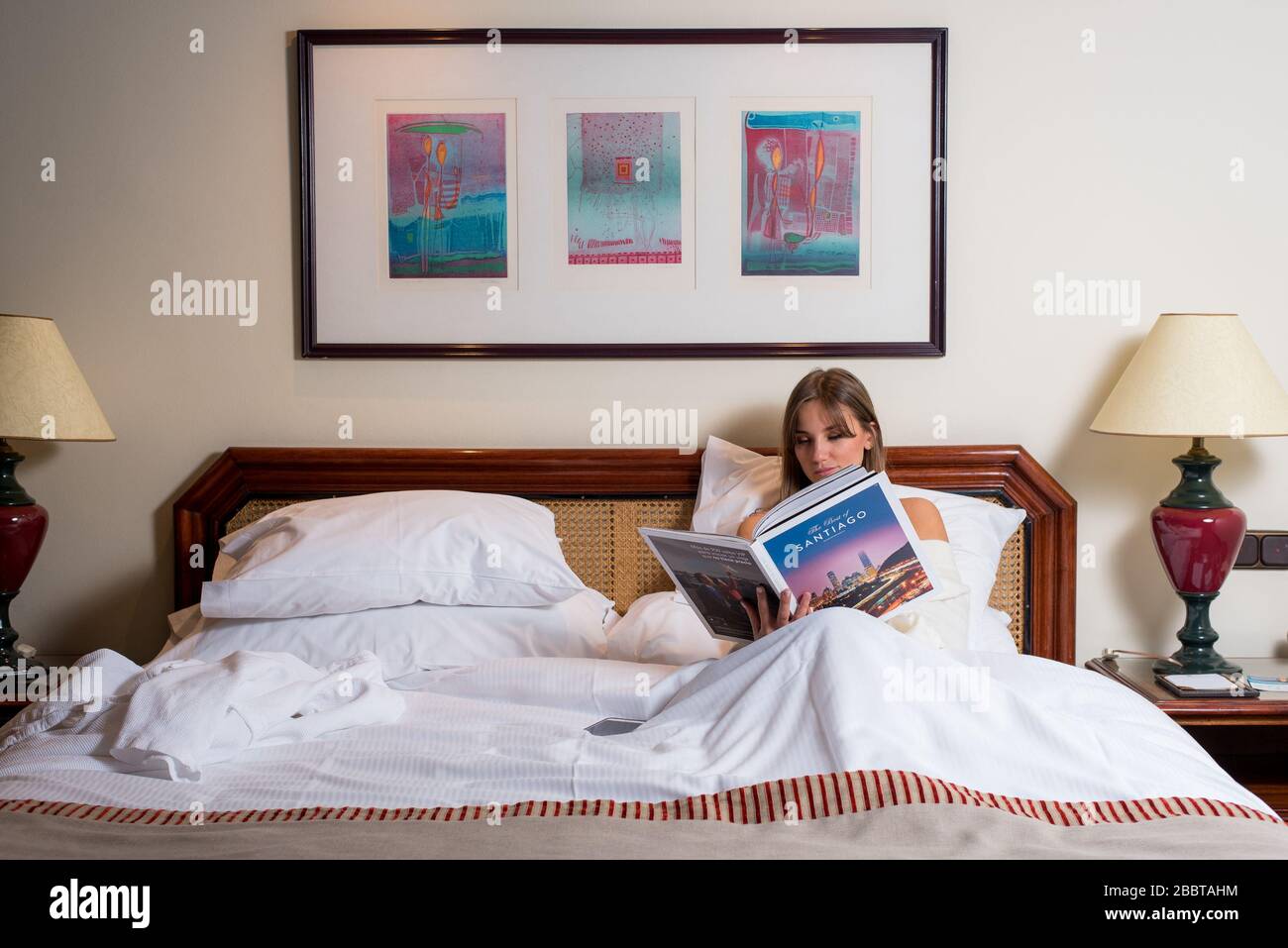 Ragazza rilassante e lettura nel letto della camera d'albergo Foto Stock