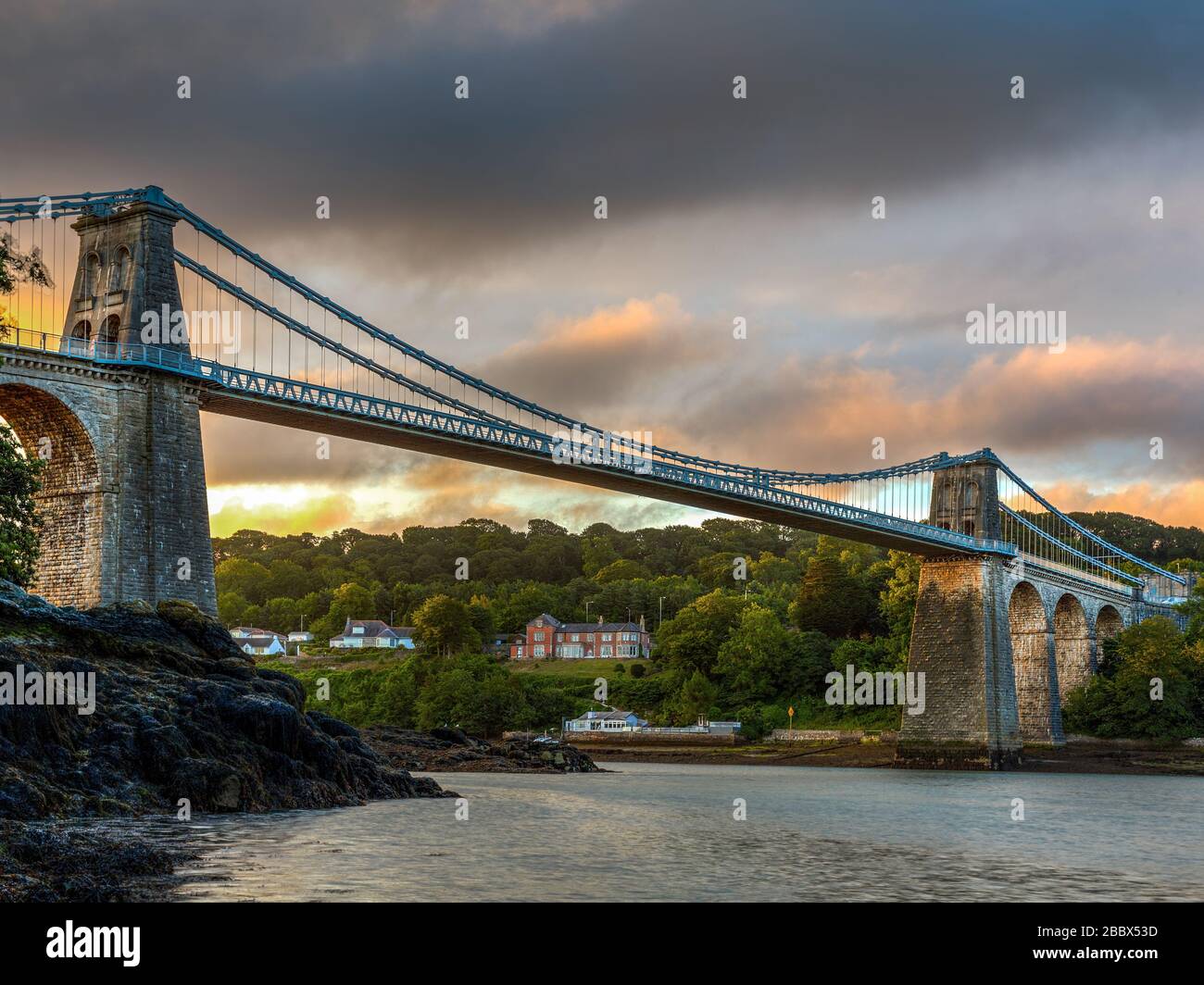 Alba al ponte sospeso Menai che collega l'isola di Anglesey con il Galles continentale, progettato da Thomas Telford e aperto nel 1826 Foto Stock