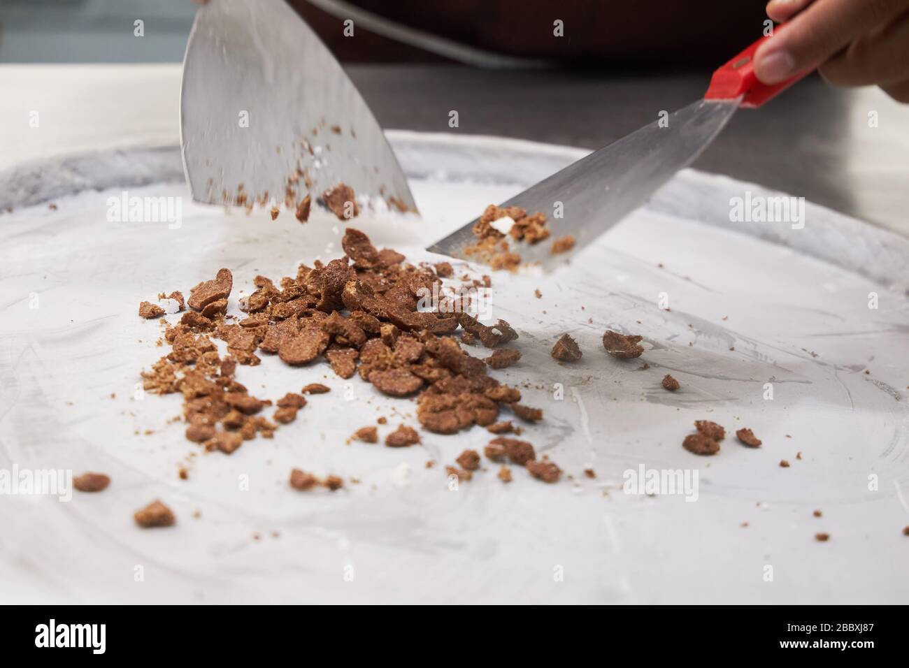 Il pasticcere mette il ripieno di gelato su una superficie metallica raffreddata. Foto Stock