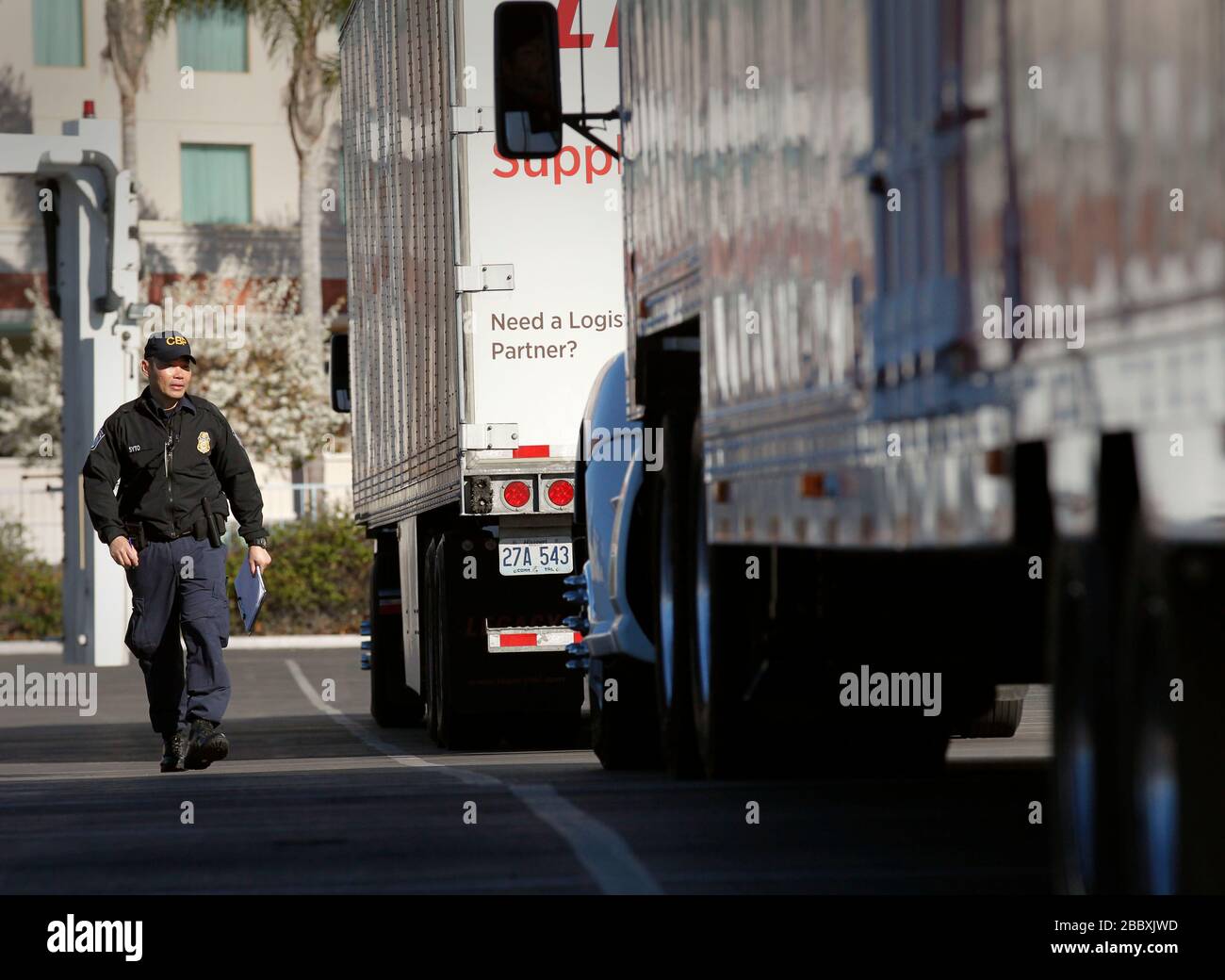 Il funzionario statunitense addetto alle dogane e alla protezione dei confini prepara una linea di autocarri per ispezioni non intrusive a raggi X al di fuori dello stadio Levi's, in quanto le operazioni di sicurezza vengono condotte prima del Super Bowl 50 a Santa Clara, California, 1° febbraio 2016. Foto Stock