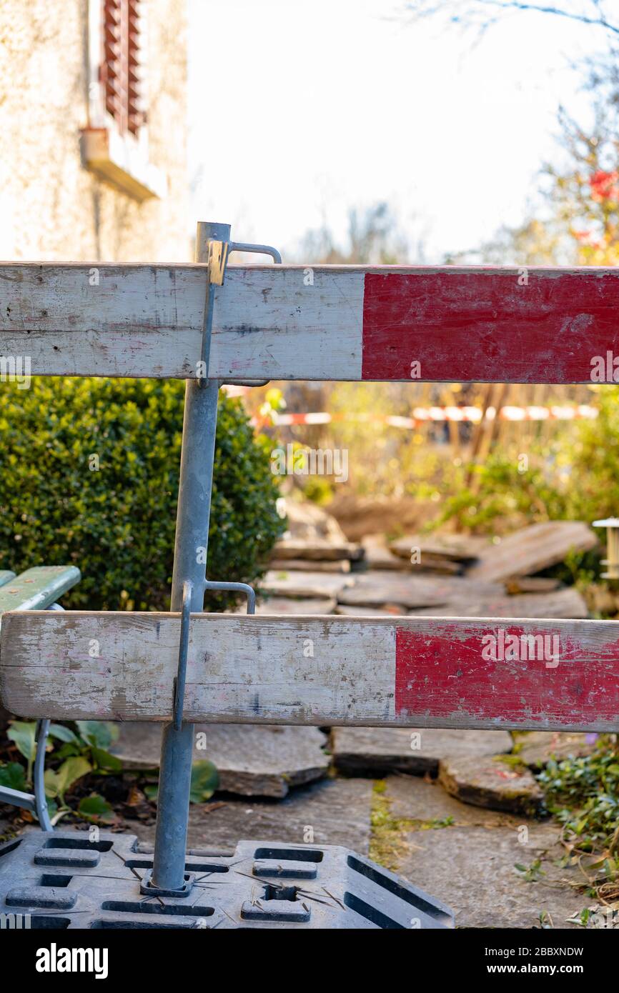 Barriera di costruzione nel cortile anteriore. Barricata per cantiere di fusto di fognatura. Focus su primo piano, per concetto. Scatto verticale. Foto Stock