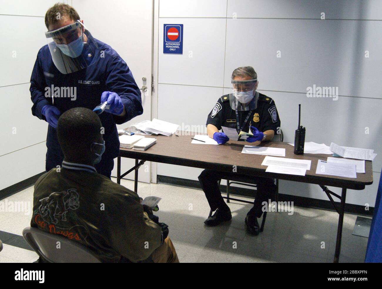 U.S.C.G. Il supervisore di CBP e Corpsman Sam Ko ha condotto misure di prescreening su un passeggero che arriva dalla Sierra Leone al terminal 5 dell'aeroporto internazionale o'Hare. Foto Stock