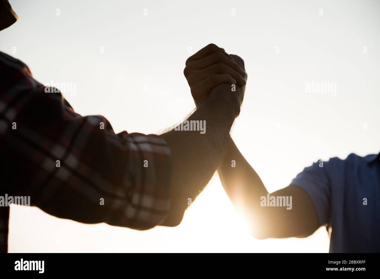 Closep up amichevole handshake, due uomini braccio wrestling mostrando unità e lavoro di squadra. Amicizia felicità tempo libero partenariato concetto di squadra. Foto Stock