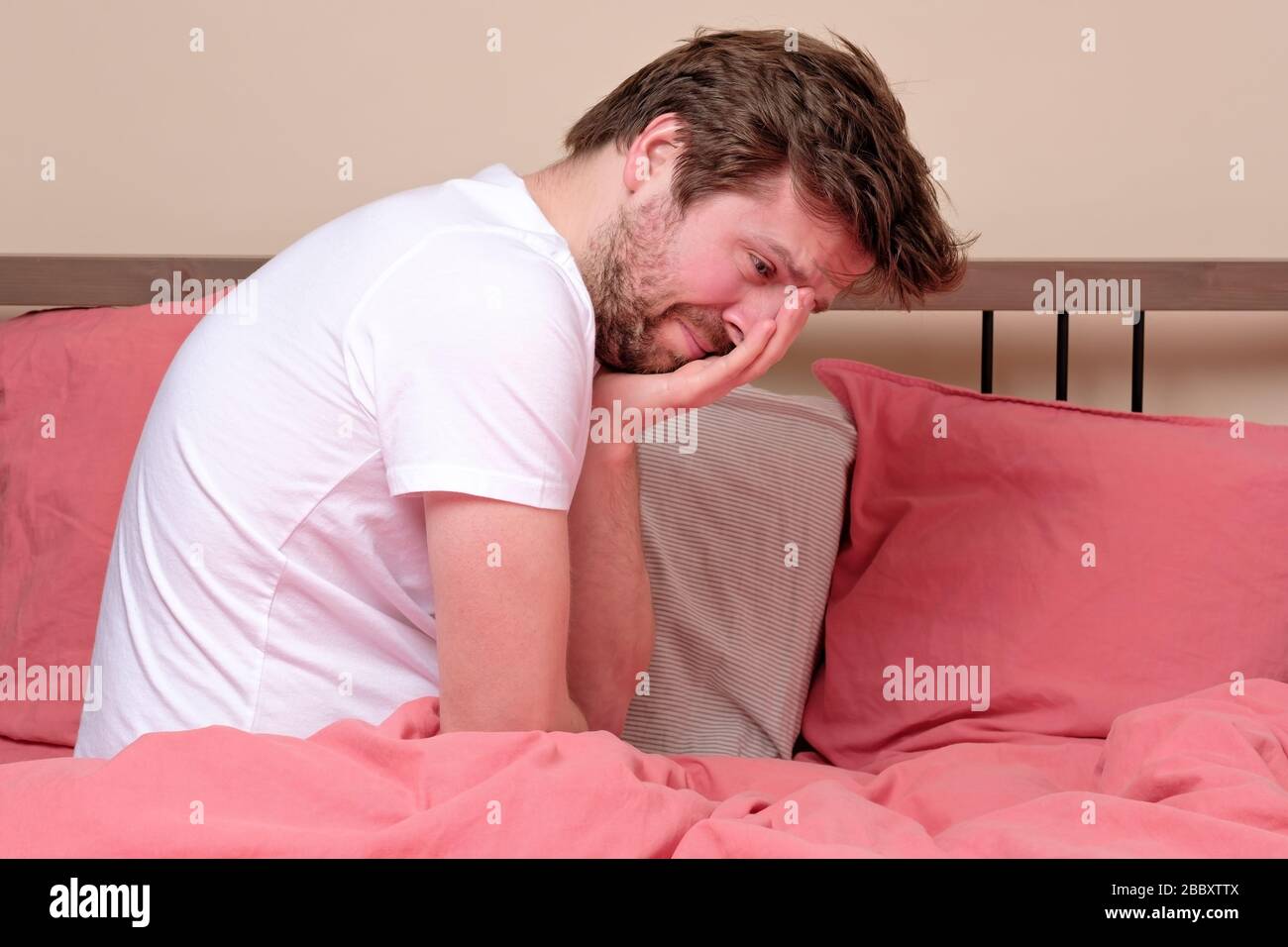 Giovane malato preoccupato seduto a letto a casa spaventoso e disperato sofferenza insonnia, depressione o crisi emotiva. Disturbo mentale, oressendo da solo co Foto Stock