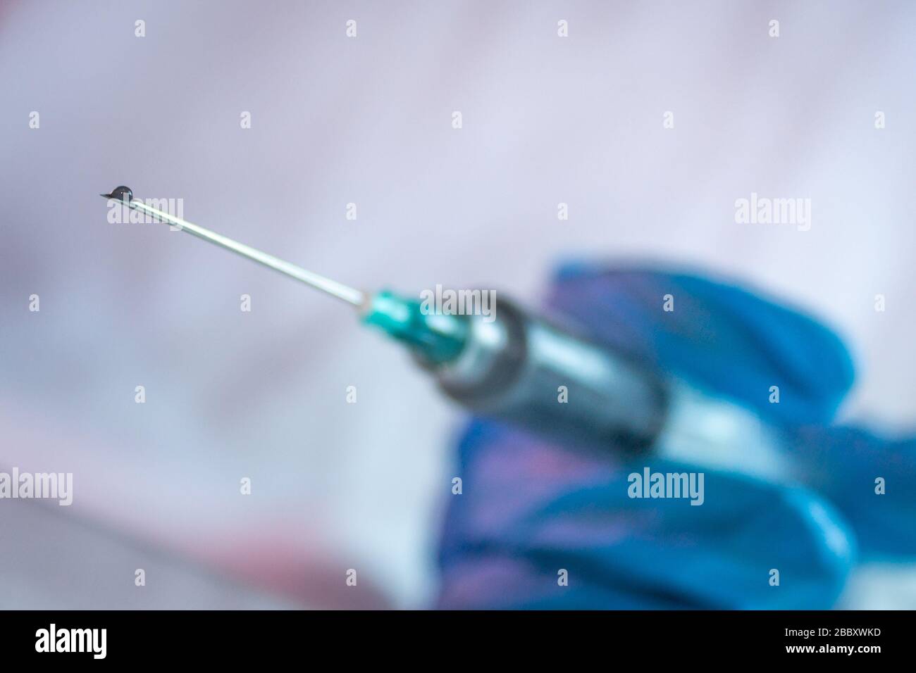 goccia di vaccino in siringa per il trattamento di covid 19 con l'uso di guanti blu 3 Foto Stock