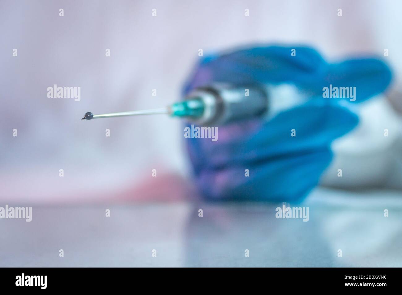 goccia di vaccino in siringa per il trattamento di covid 19 con l'uso di guanti blu 5 Foto Stock