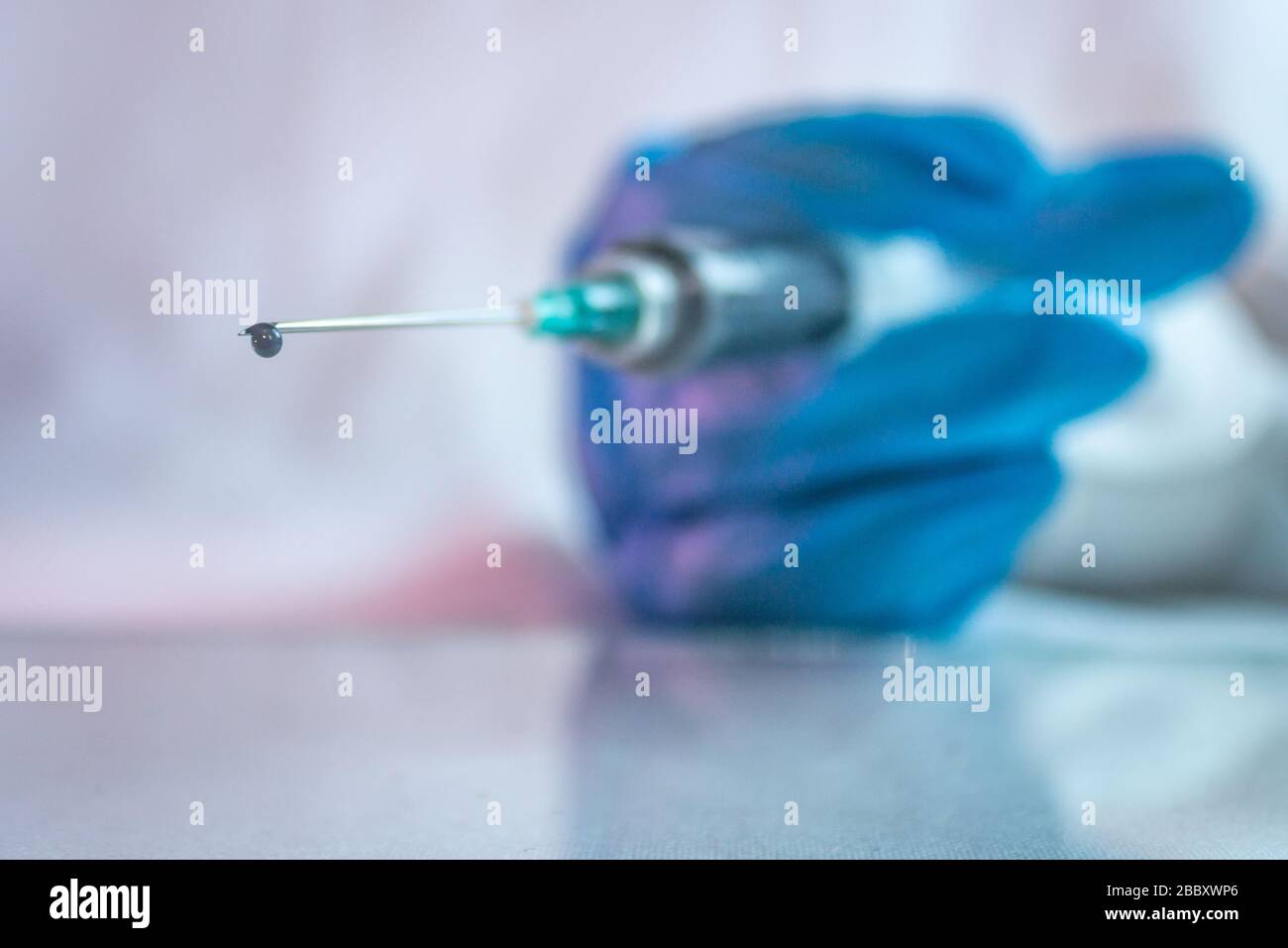 goccia di vaccino in siringa per il trattamento di covid 19 con l'uso di guanti blu 7 Foto Stock