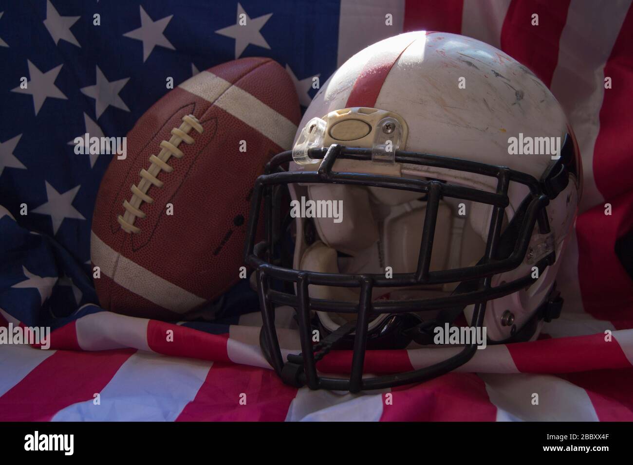 Pallone da calcio americano e casco con bandiera degli Stati Uniti sullo sfondo Foto Stock