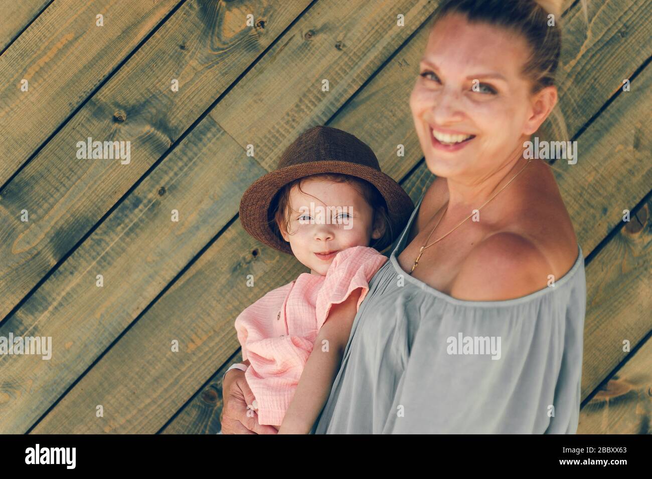 Emozione ritratto nonna e sua nipote in stile rurale mussola cluthers su sfondo verde di legno. Concezione familiare. Messa a fuoco morbida selettiva. Foto Stock
