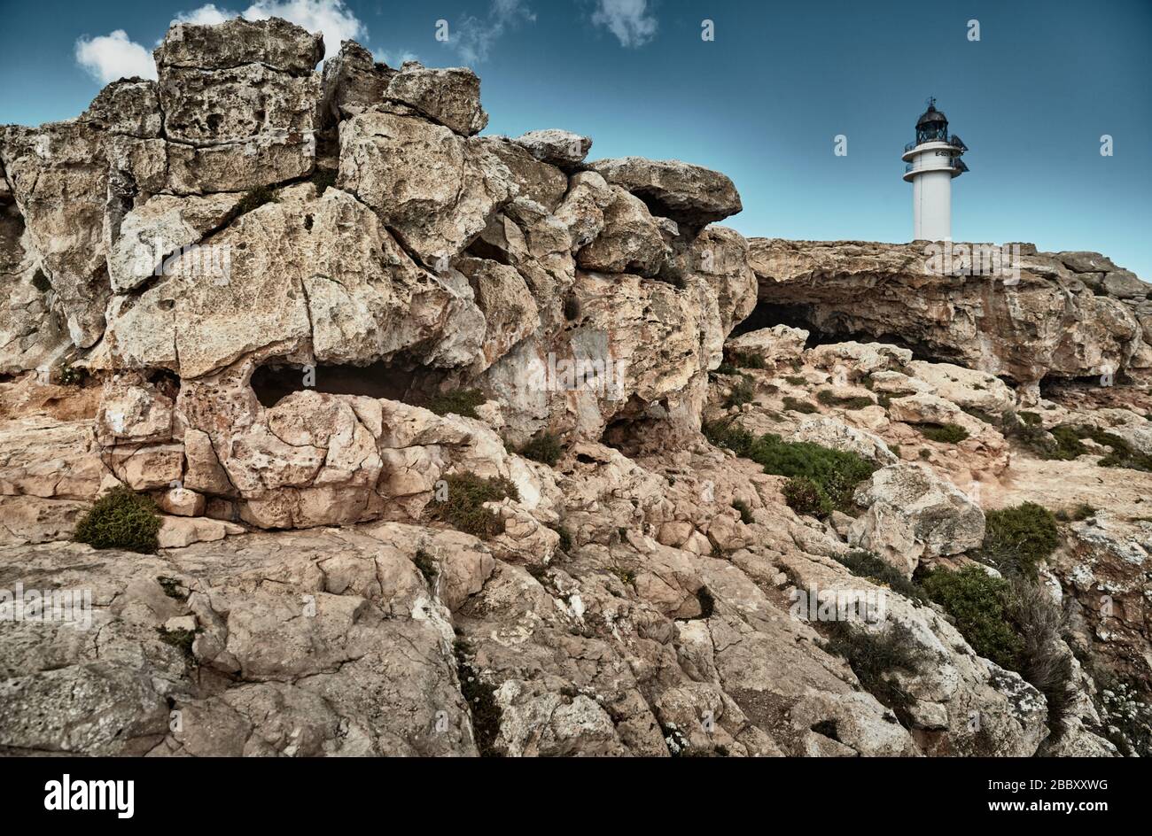 Faro sull'isola di Formentera, Spagna, il cielo blu con nuvole bianche, senza persone, rocce, pietre, tempo soleggiato Foto Stock