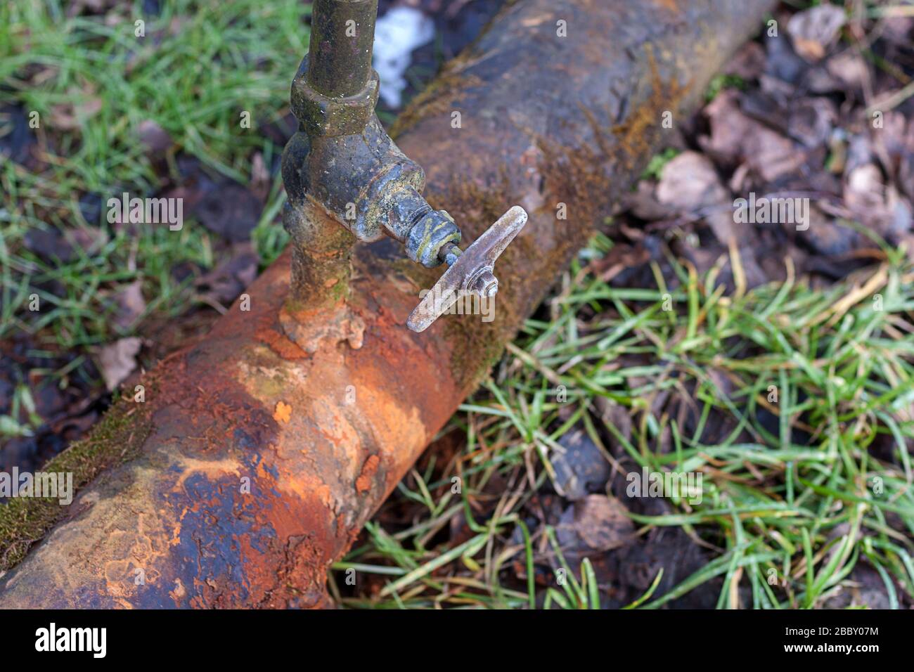 tubo dell'acqua arrugginita con rubinetto che perde Foto Stock