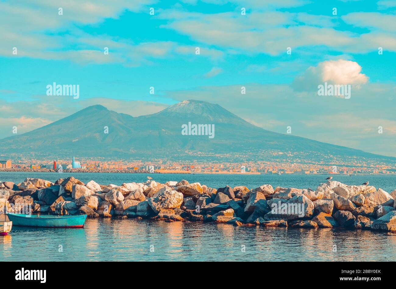 Vista sul Vesuvio e sul Golfo di Napoli con rocce e barca blu. Napoli,  Italia Foto stock - Alamy