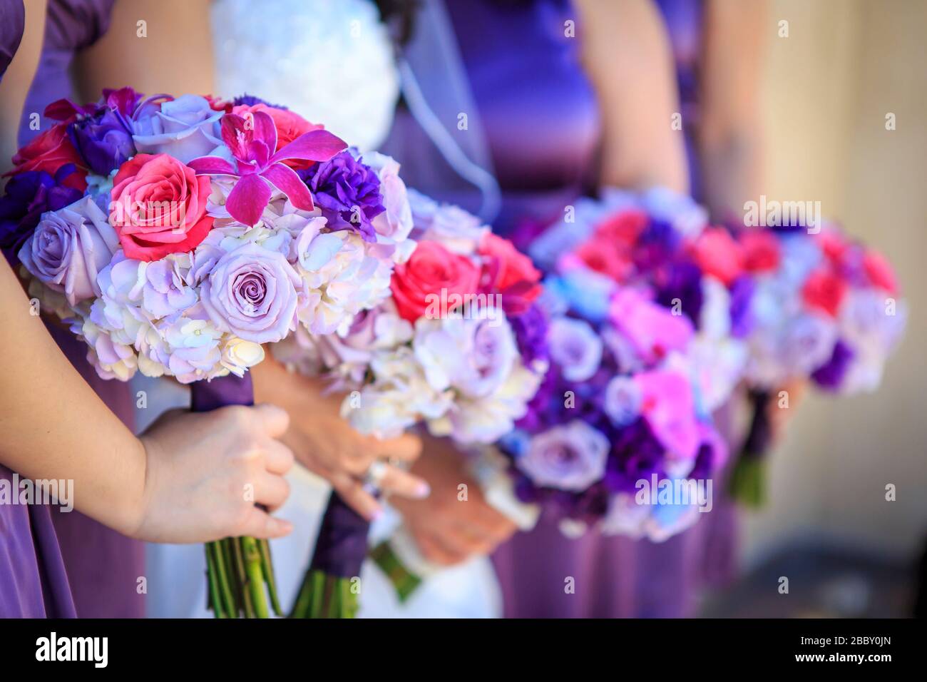 Lavendar, rosa e bianco rose e fiore tenuto da bridesmaid in piedi in una linea Foto Stock