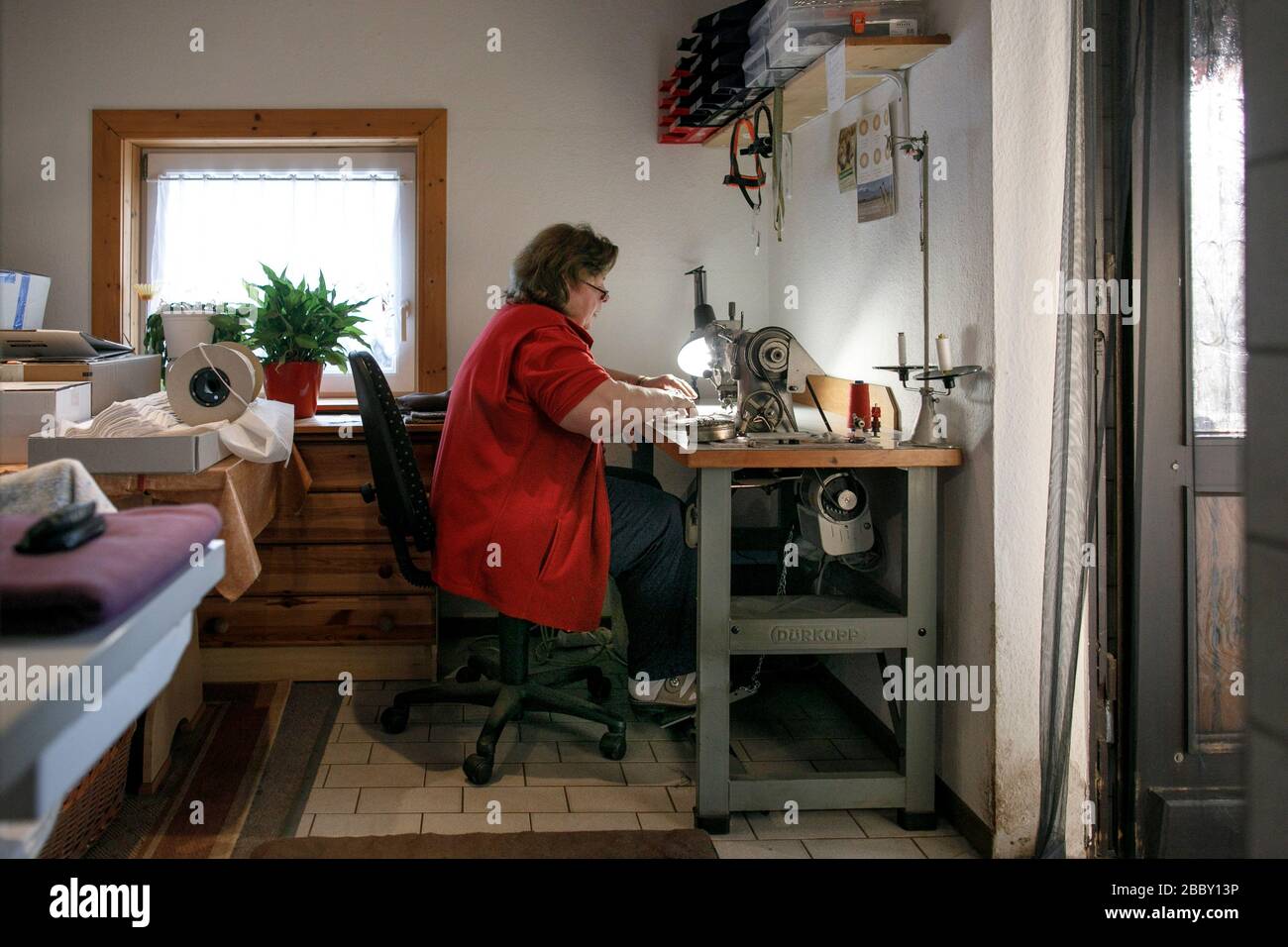 Strausberg, Germania. 27th Mar, 2020. Kerstin Hiebsch, sarto, cuce una maschera bocca-naso dopo quello fatto in casa per il produttore berlinese di cravatta Auerbach. Dalla scorsa settimana, vari modelli di maschere a naso di bocca realizzati con tessuti diversi sono stati venduti dal produttore di cravatta. (A 'la protezione di Sud invece dei legami di seta: Produzione cambia produzione') credito: Carsten Koall/dpa/Alamy Live News Foto Stock