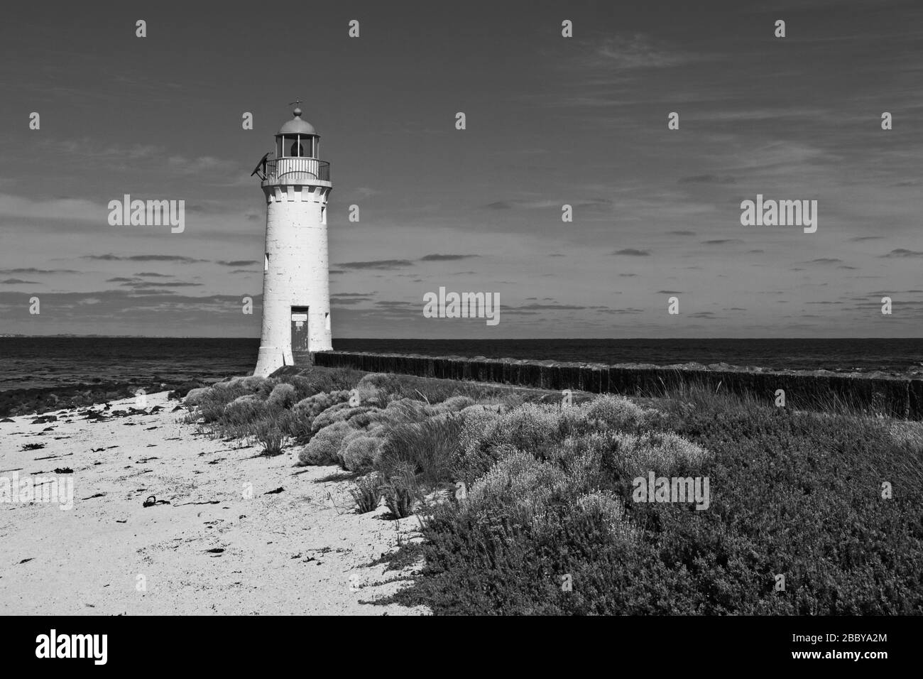 Una vista in bianco e nero del faro di Port Fairy, bianco netto contro il mare e il cielo Foto Stock