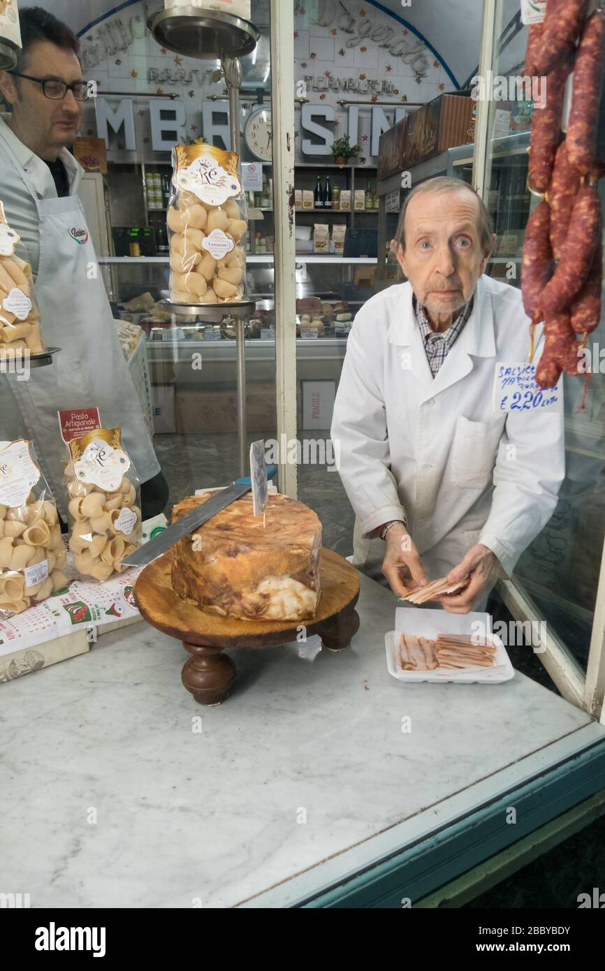 Macellaio che prepara una porzione di prosciutto nella sua vetrina a Napoli. Foto Stock