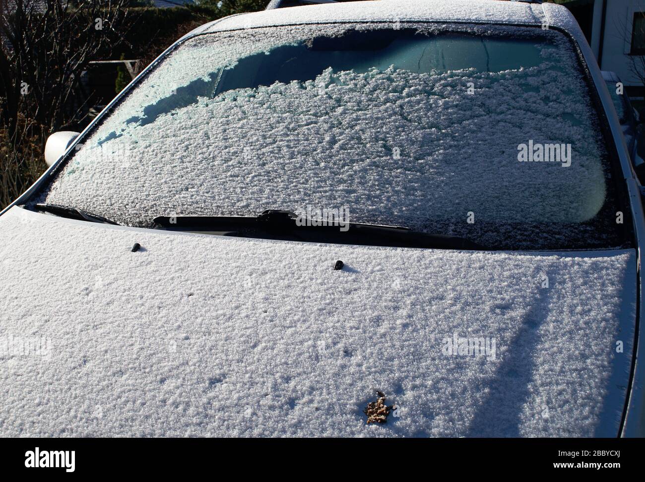 neve sul parabrezza della macchina in una mattinata di sole Foto Stock