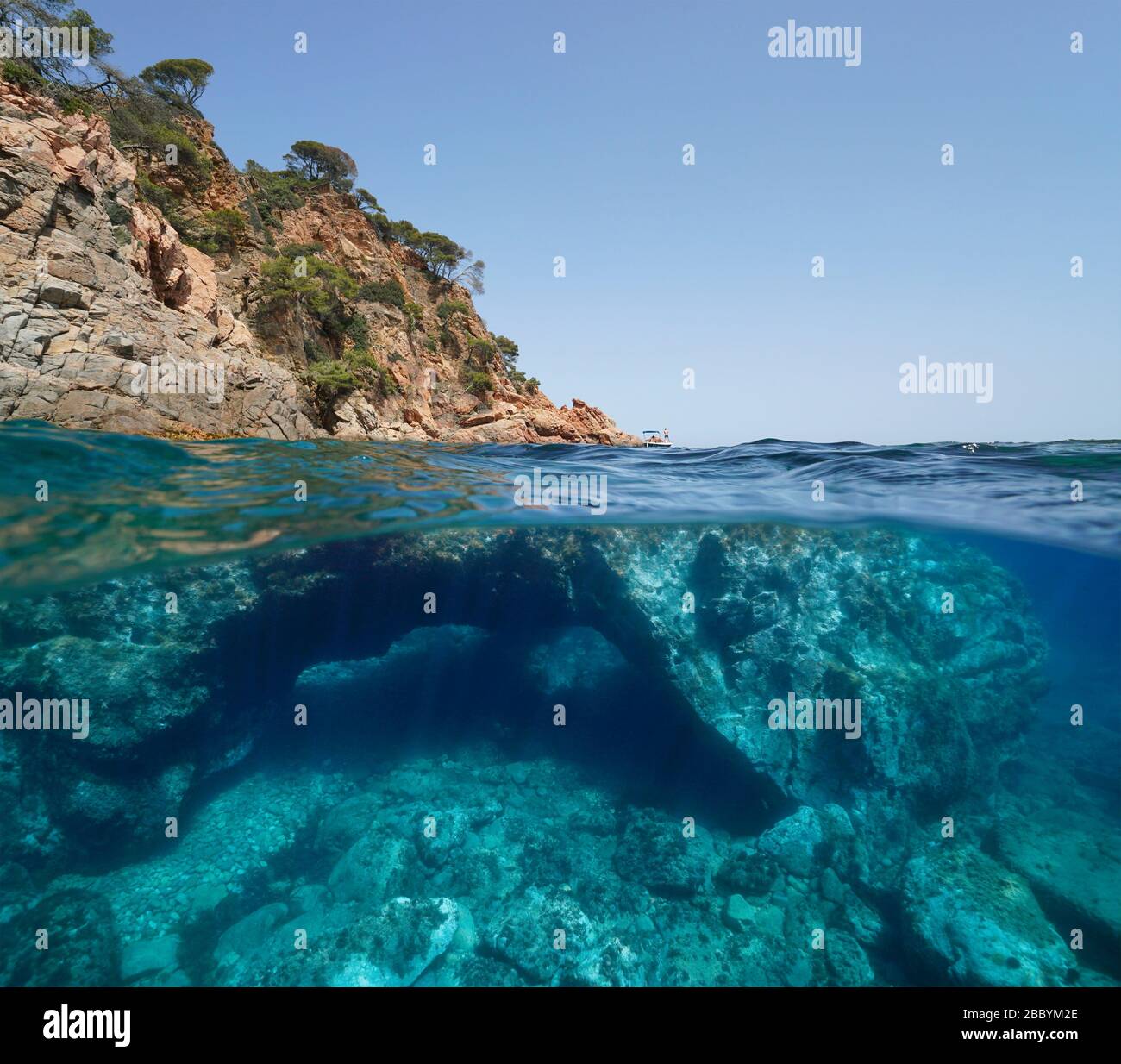 Costa rocciosa e grande roccia con un buco sott'acqua, vista su e sotto l'acqua, Mar Mediterraneo, Spagna, Costa Brava, Catalogna Foto Stock