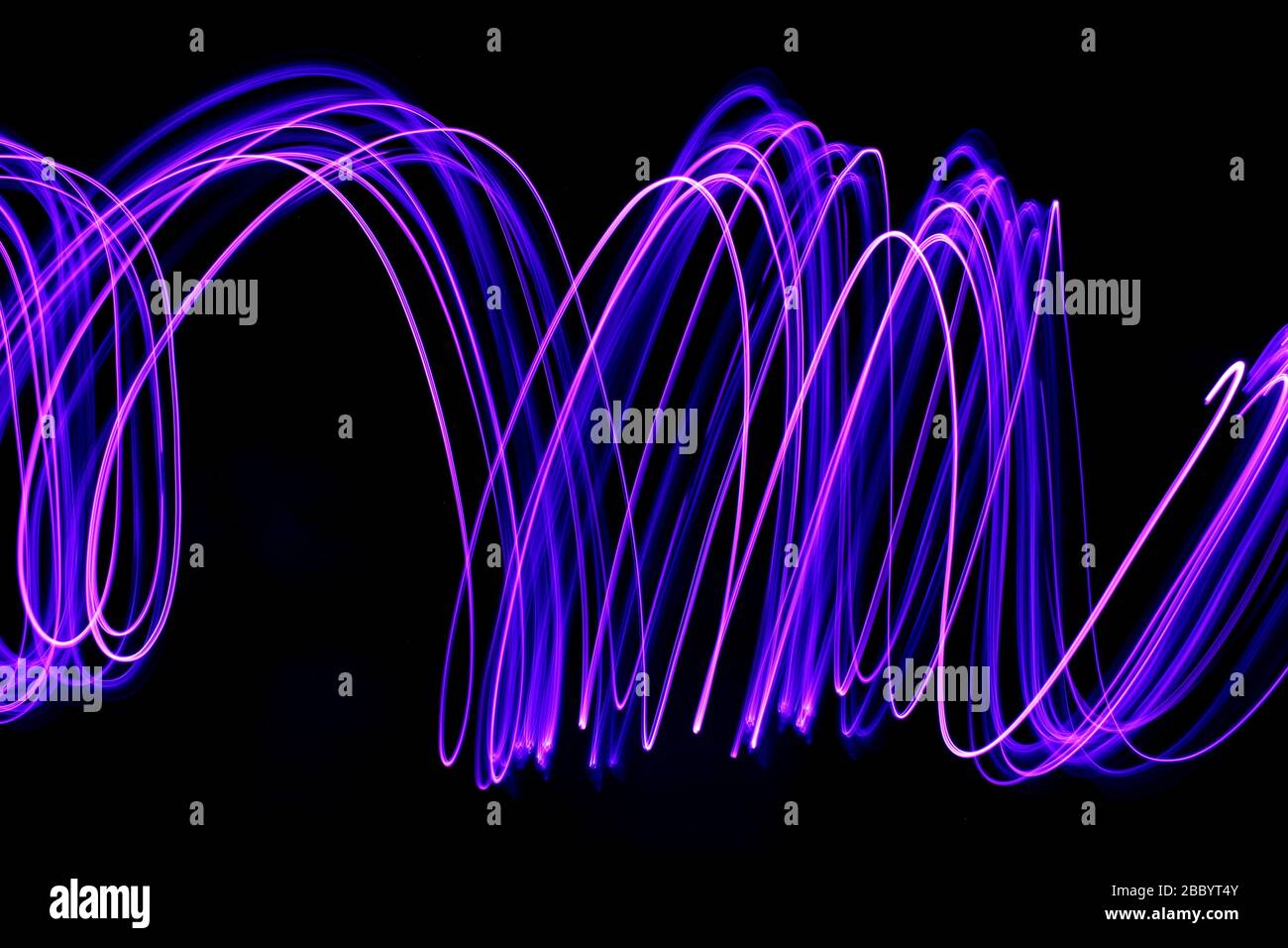 Foto a lunga esposizione di colore viola neon in un disegno astratto di linee parallele su sfondo nero. Fotografia di pittura leggera. Foto Stock