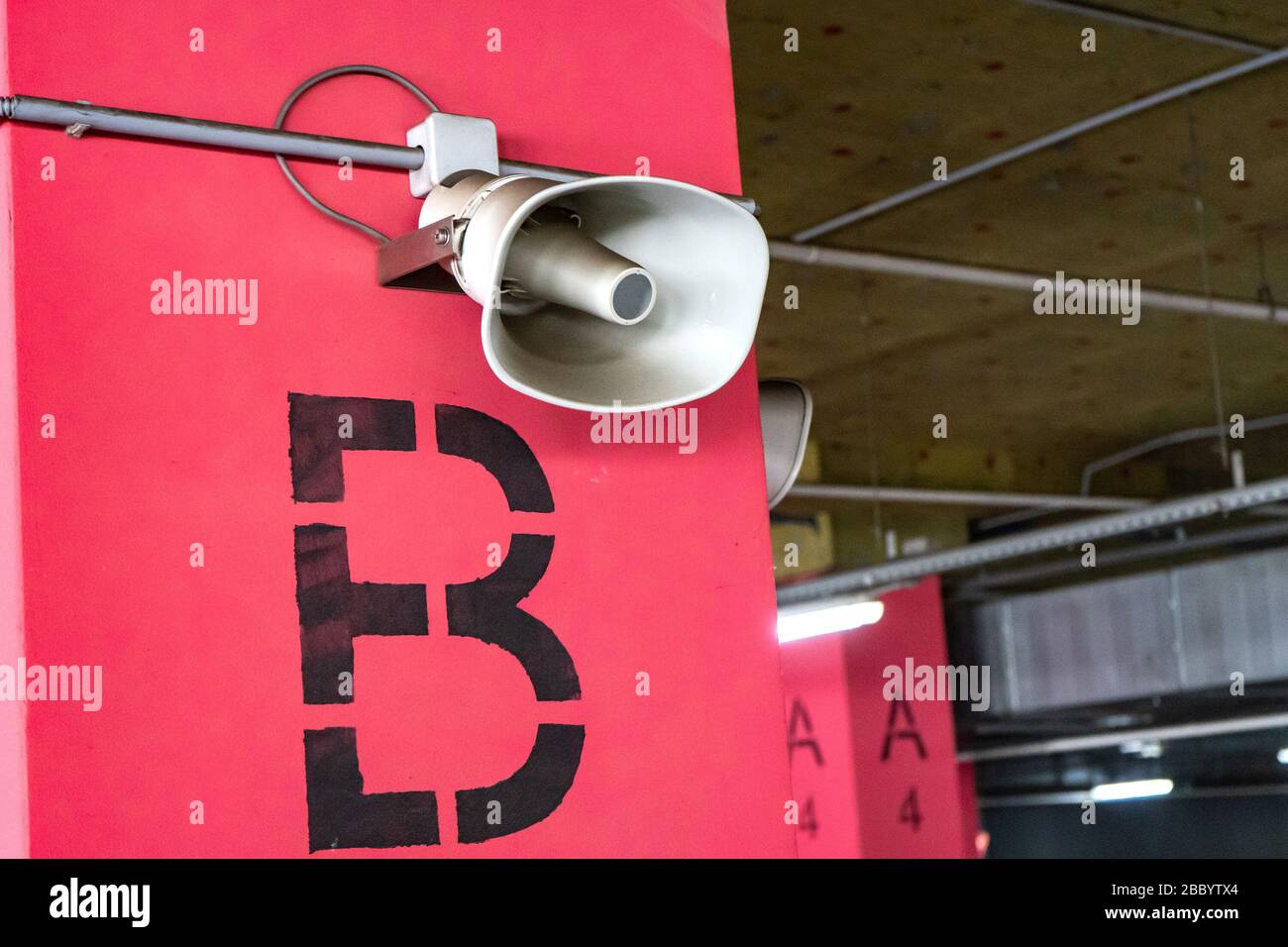Sistema di allerta per la popolazione. Montato su pali di cemento sotto il soffitto di un edificio per informare un'organizzazione o comunità. Parcheggio sotterraneo Foto Stock