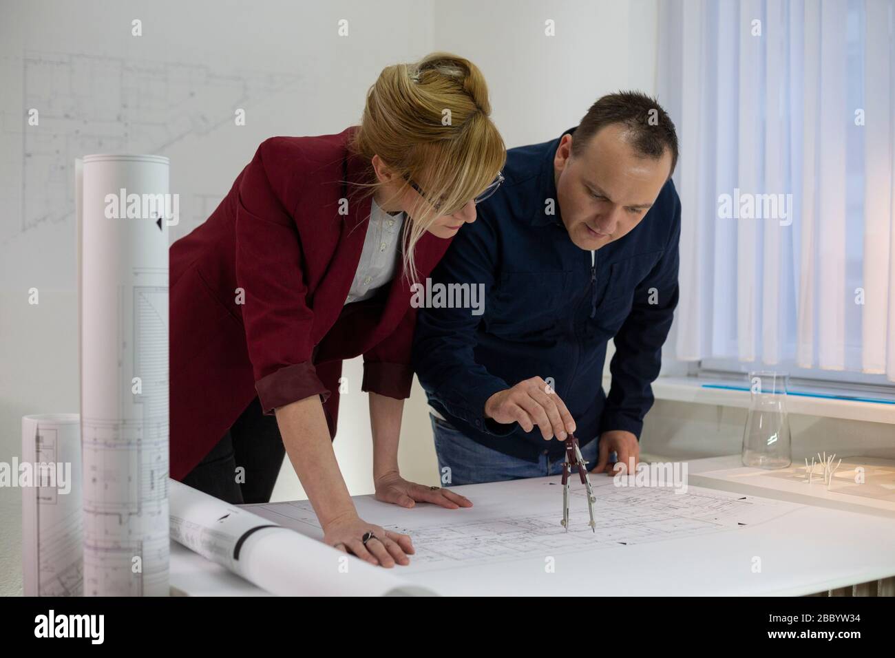 Due Architetti in ufficio alla scrivania che guardano su un progetto. Designer attenti con occhiali pensare e discutere del progetto. Foto Stock