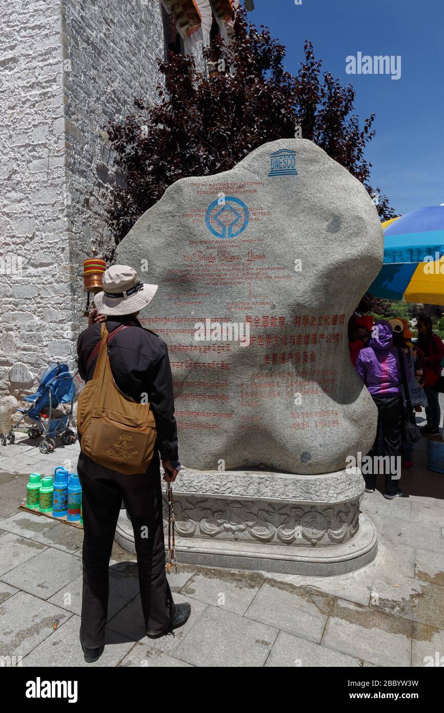 Il turista si erge di fronte alla roccia con l'iscrizione del Potala Palace come sito patrimonio dell'umanità dell'UNESCO. Una destinazione e centro di viaggio in popluar Foto Stock