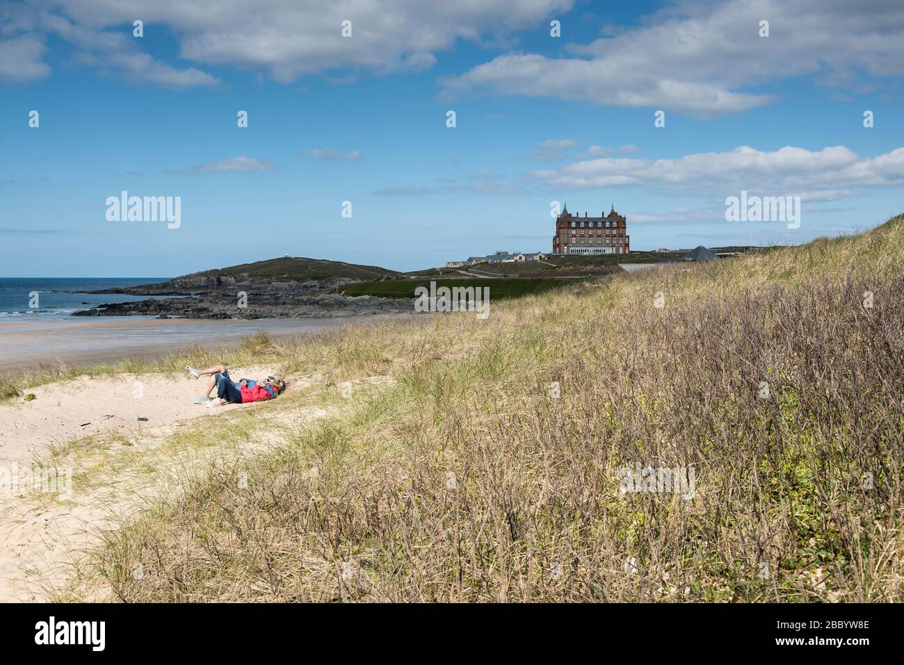 Un paio di relax insieme nel sistema di dune di sabbia che si affaccia Fistral Beach a Newquay in Cornovaglia. Foto Stock