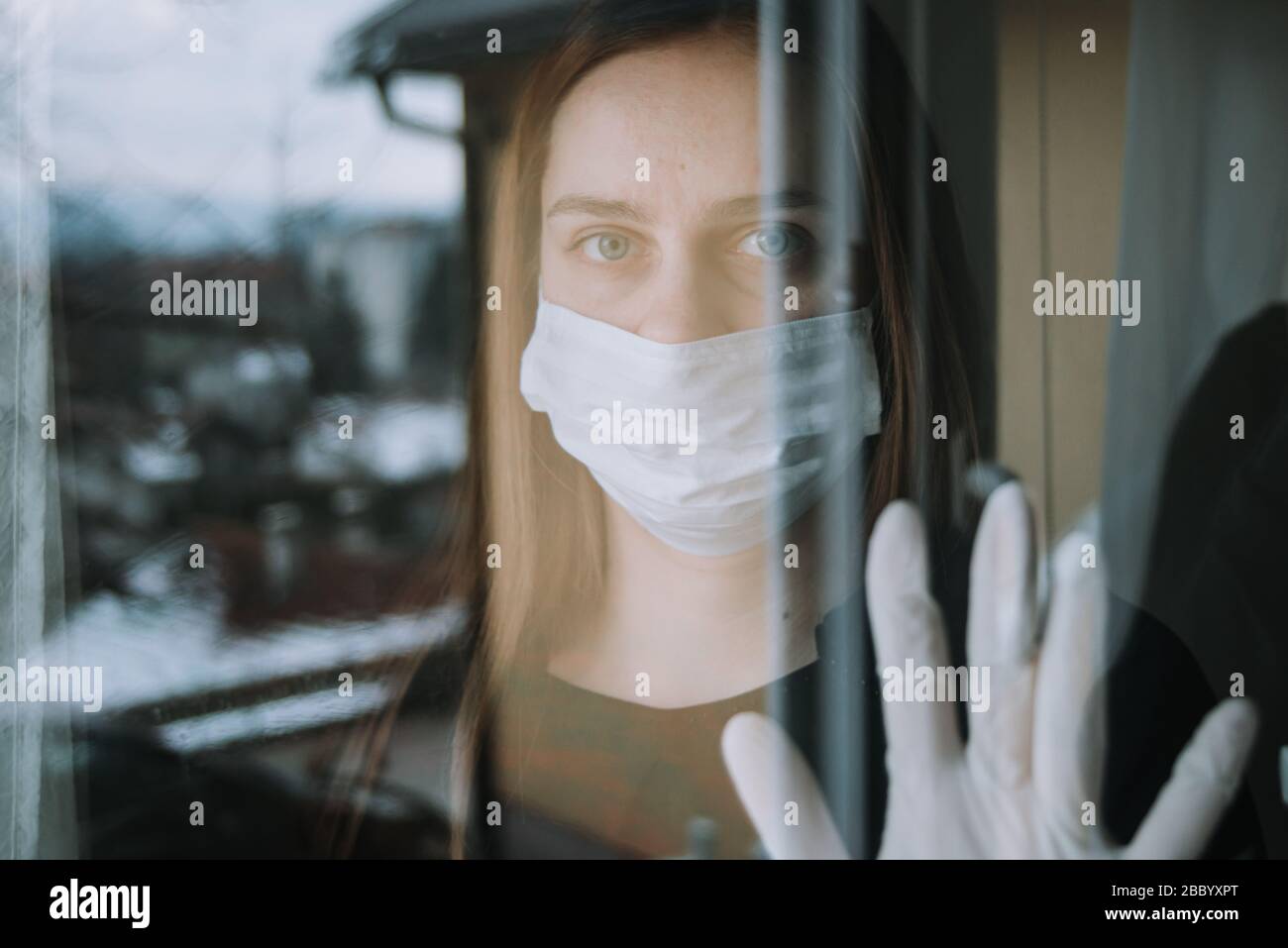 donna in quarantena vedendo il suo fritto che è venuto a visitarla a causa di coronavirus covid-19 maschera di spirito e guanti sulla finestra a casa Foto Stock