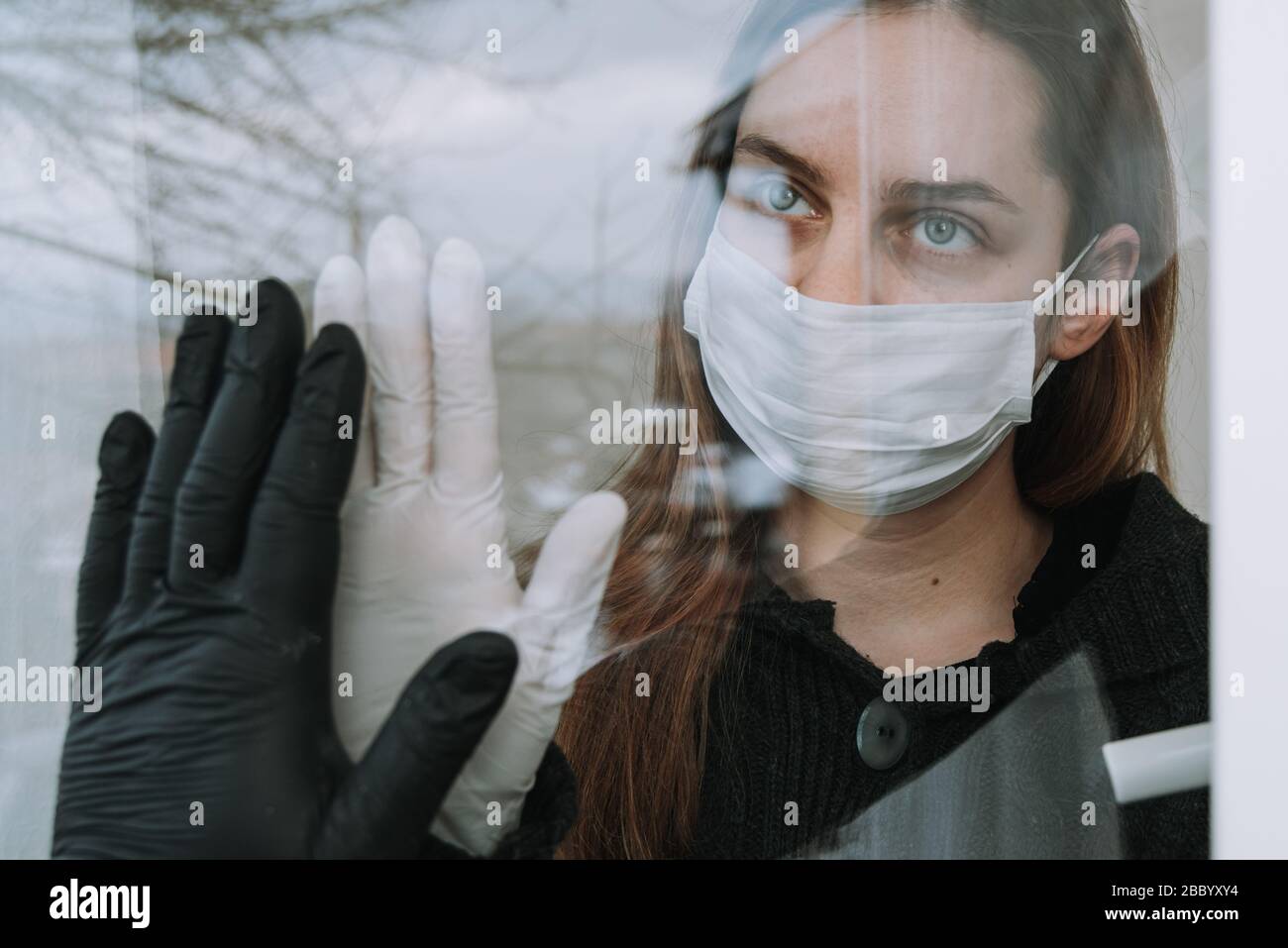 donna in quarantena vedendo il suo fritto che è venuto a visitarla a causa di coronavirus covid-19 maschera di spirito e guanti sulla finestra a casa Foto Stock