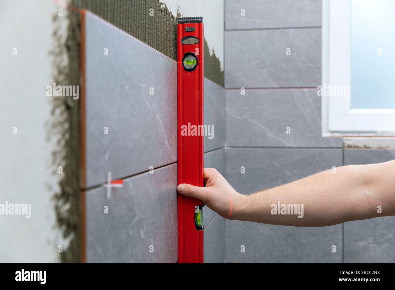 piastrelle per bagno - tiler controllare il livello di muro piastrellato Foto Stock
