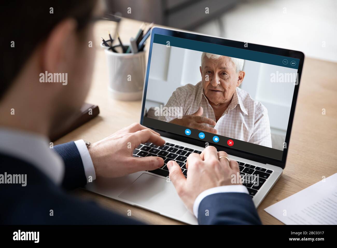 Il dipendente di sesso maschile parla con il padre anziano sulla webcam del notebook Foto Stock