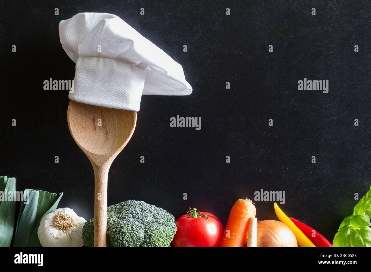 Cappello dello chef sul cucchiaio e verdure cucina cibo di fondo concetto Foto Stock