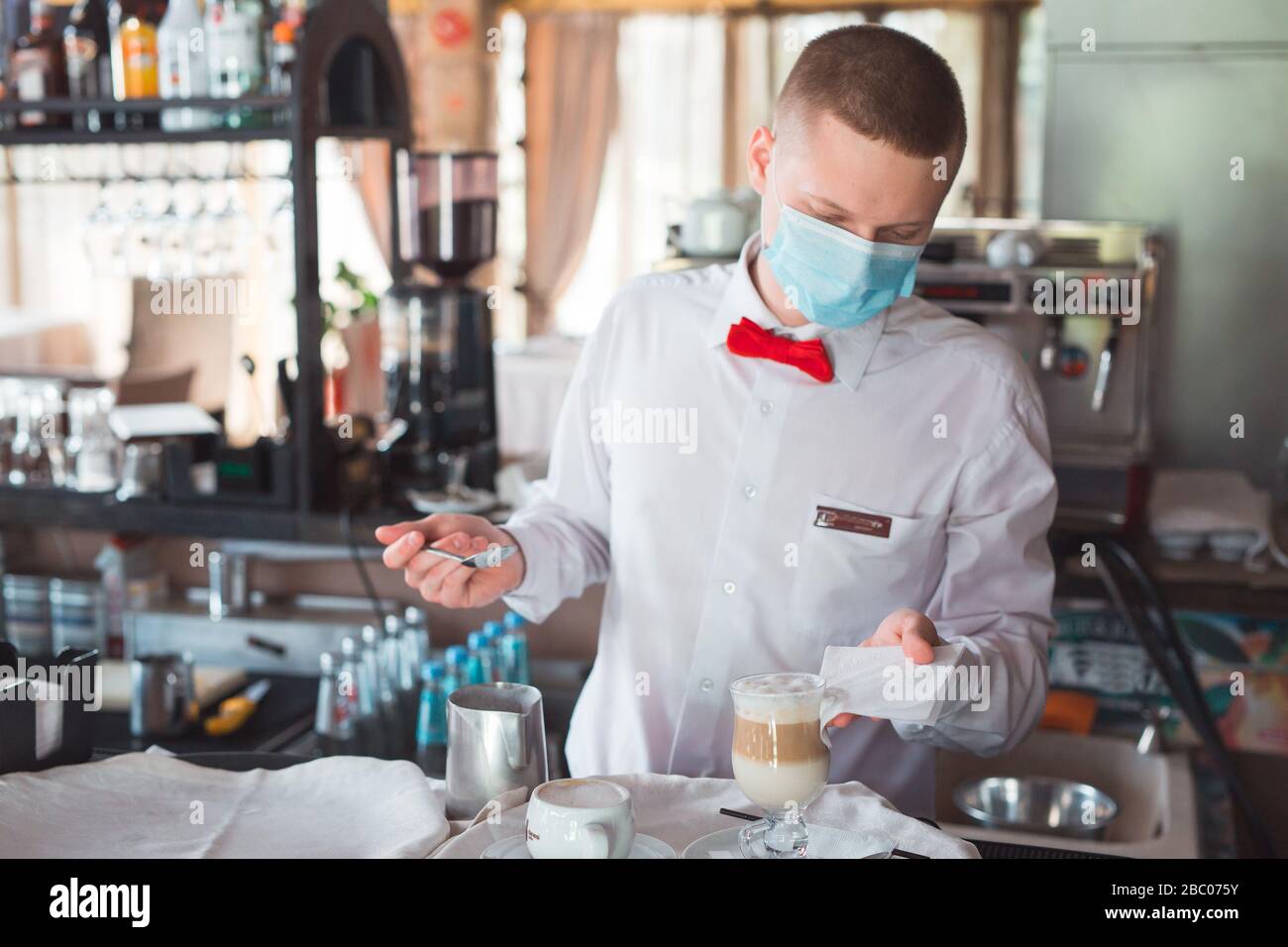 il cameriere lavora in un ristorante in una maschera medica Foto Stock