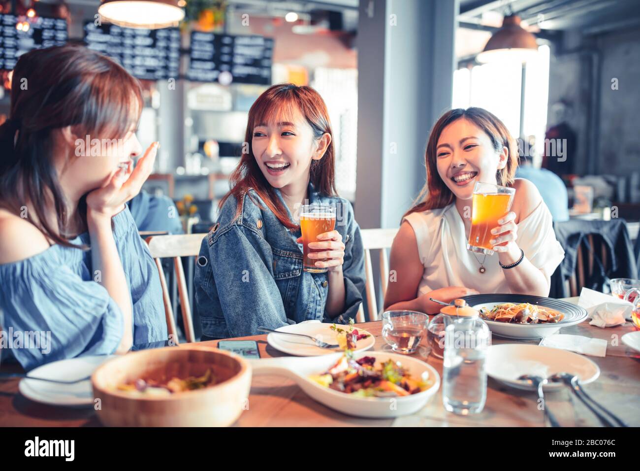giovane donna felice seduto nel ristorante e godere la cena e la birra Foto Stock