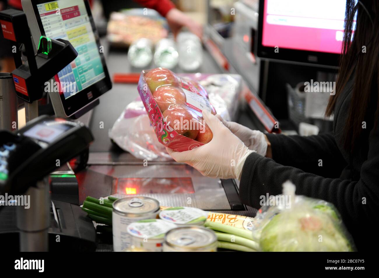 Shopping alimentare in tempi della pandemia Corona: Nella foto un cassiere con guanti di protezione al lavoro in un ramo della catena di supermercati Rewe in Obergiesing. [traduzione automatica] Foto Stock