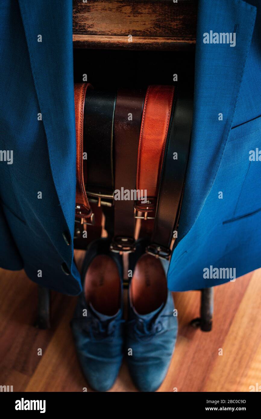 Una giacca su appendiabiti con diverse cinture tra cui scegliere e scarpe corrispondenti sul fondo. Abito, Business, stile, moda, abbigliamento, outfit Foto Stock