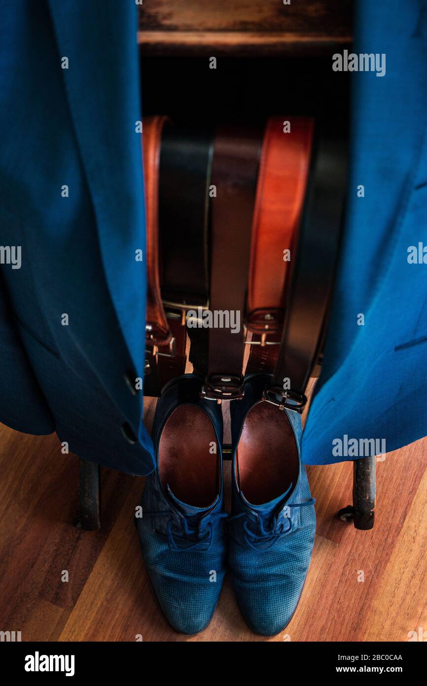 Una giacca su appendiabiti con diverse cinture tra cui scegliere e scarpe corrispondenti sul fondo. Abito, Business, stile, moda, abbigliamento, outfit Foto Stock