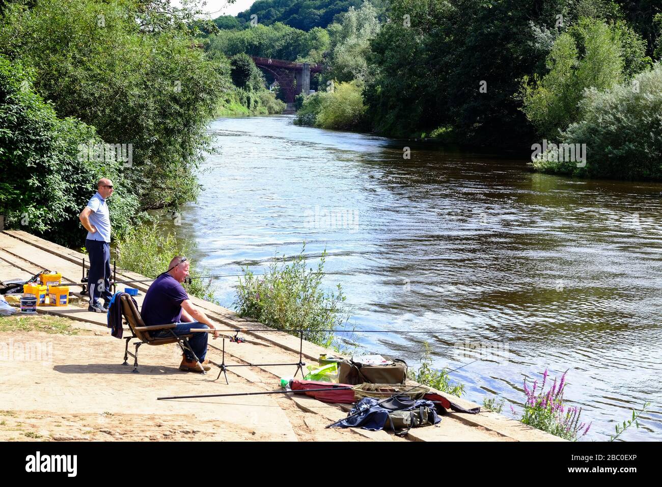 Due uomini che pescano sul fiume Severn a valle del famoso Iron Bridge a Shropshire, Regno Unito Foto Stock