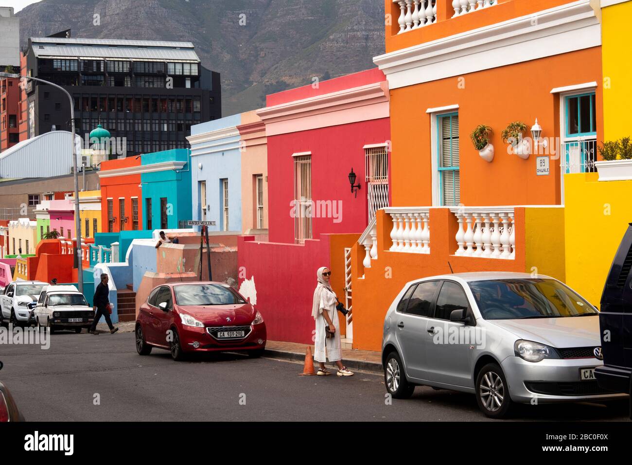 Sud Africa, Città del Capo, Schotsche Knof, Bo Kaap, Wale St, donna guardia parcheggio auto spazio di colorfully dipinto restaurato casa Foto Stock